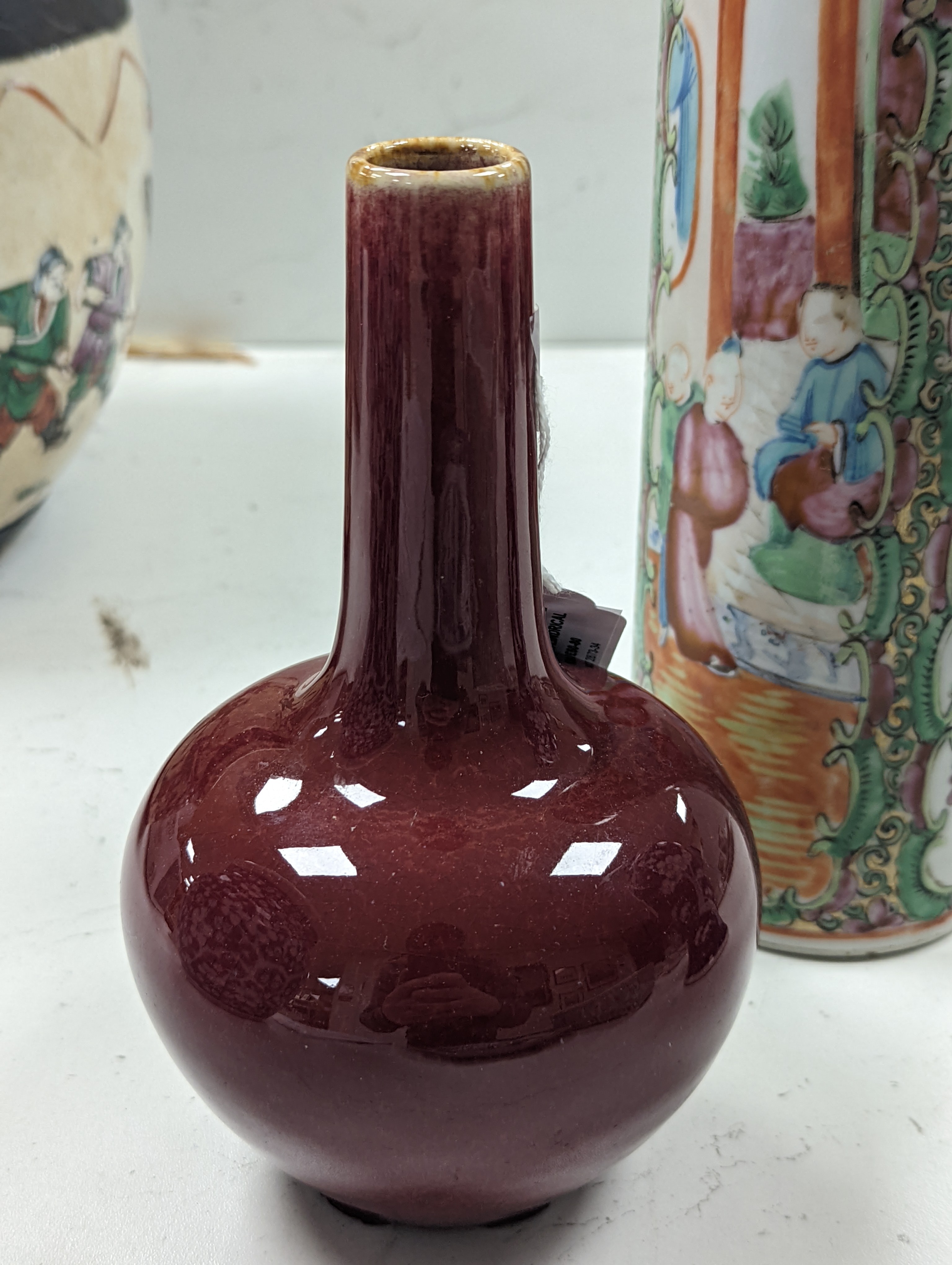 A Chinese famille rose cylindrical vase and a flambé bottle vase vase, tallest 24 cm